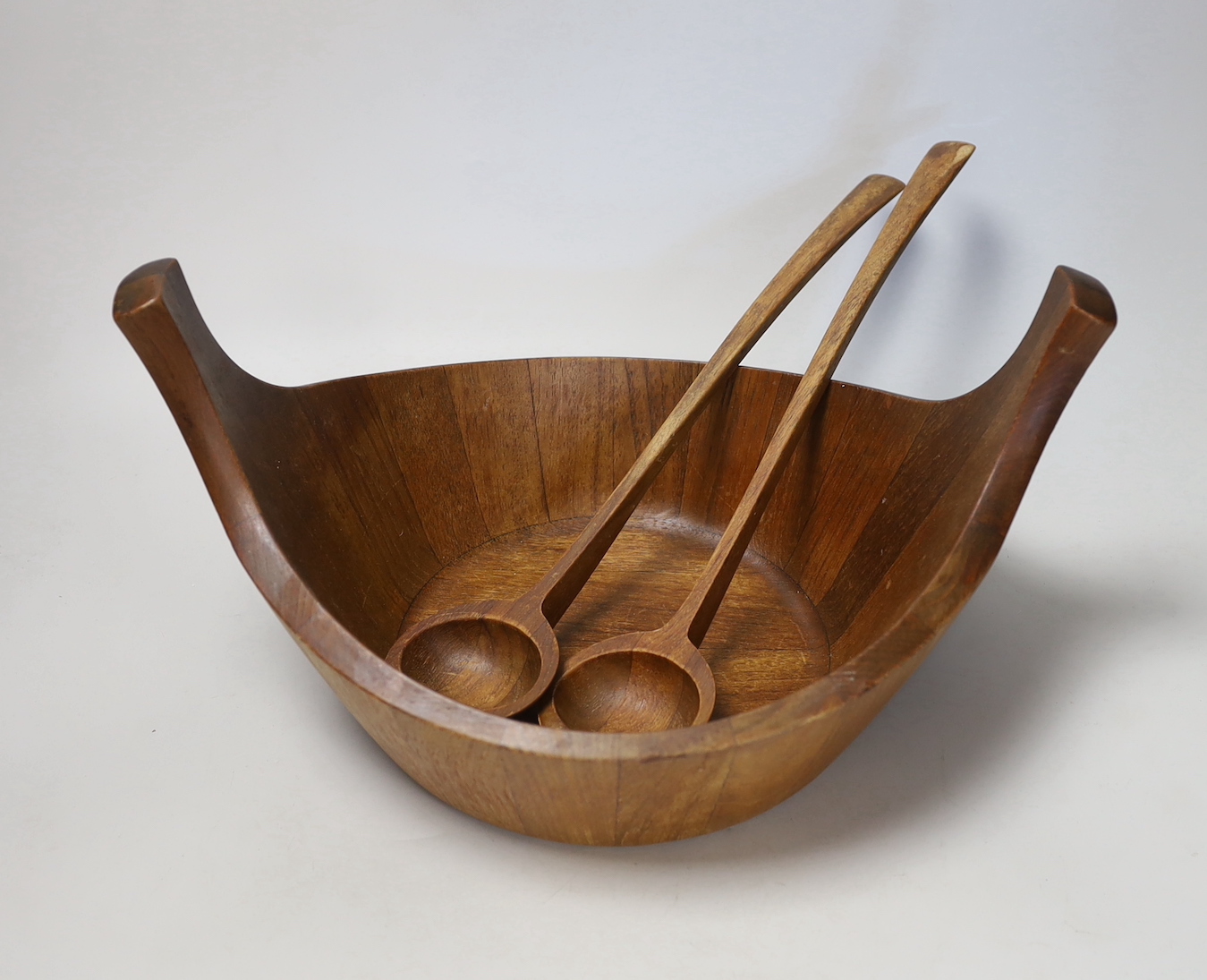 A Jens Quistgaard, for Dansk designs, Danish salad bowl with raised handles and a pair of salad servers, circa 1950's, designed in staved teak, 37cm wide